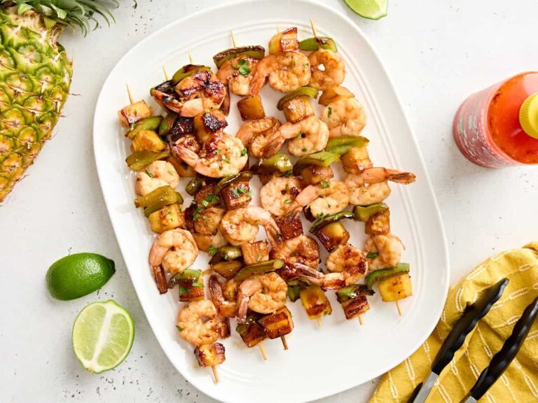 Overhead view of a platter of grilled shrimp and pineapple skewers.