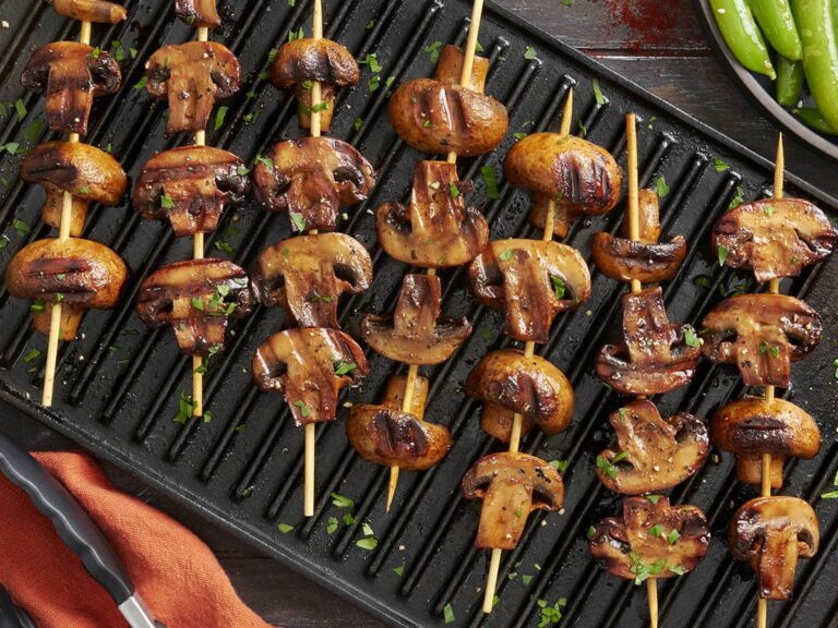 Overhead view of smoky grilled mushroom kebabs on a grill.
