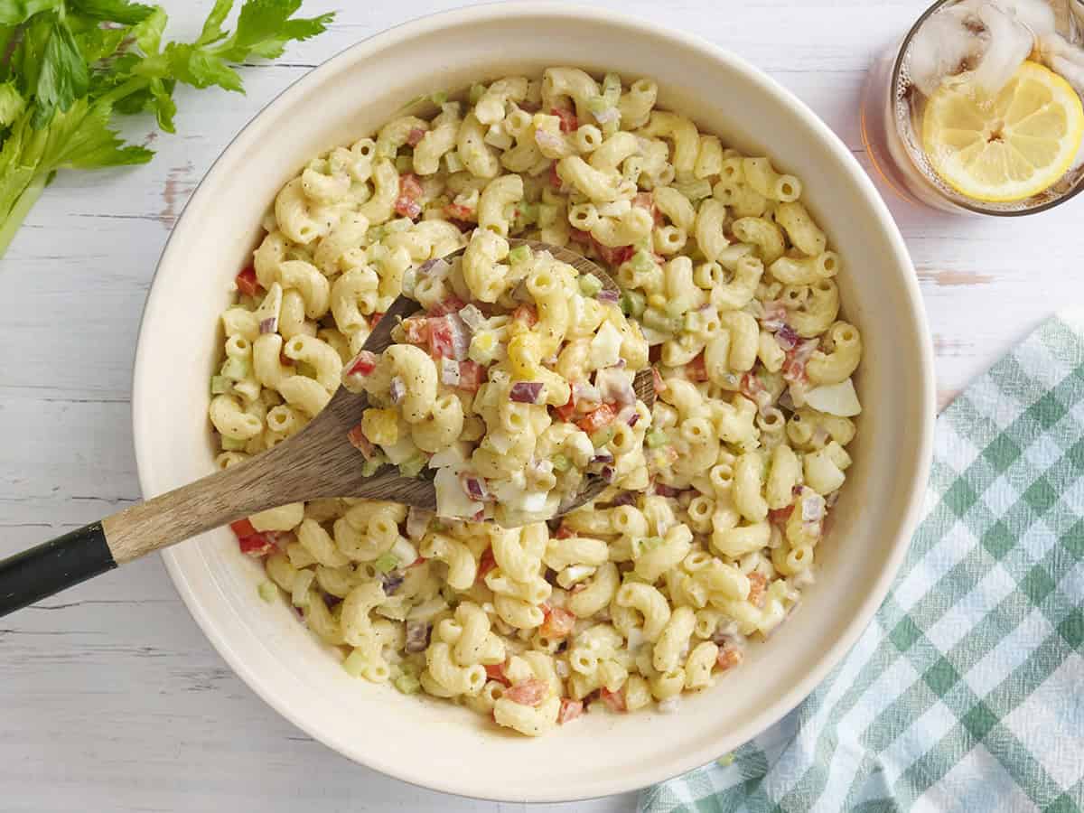 Vue aérienne d'un bol de salade de macaroni avec une cuillère en bois en prenant.