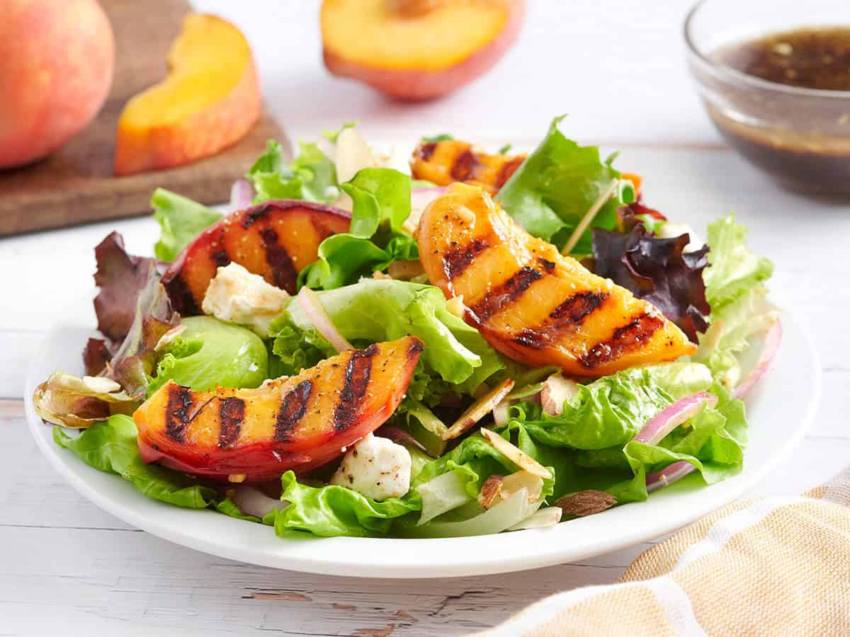 Side view of a grilled peach salad on a plate.