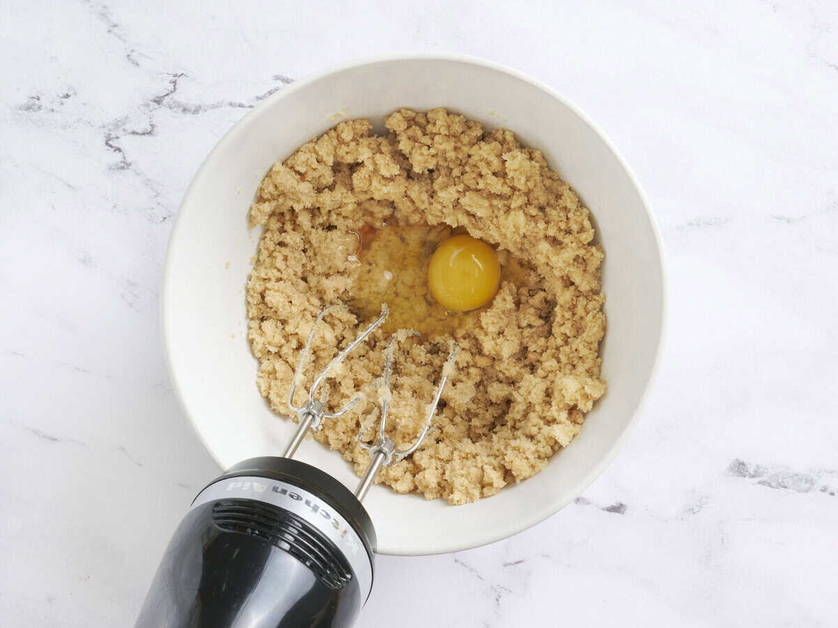 Ajouter ajouté à un bol de beurre à la crème et de sucre mélangé avec un batteur à main.