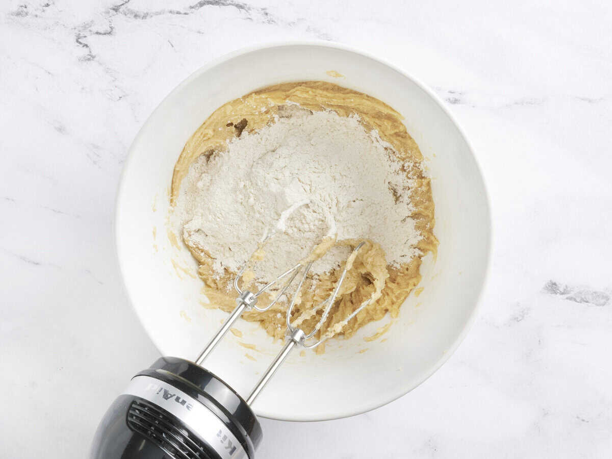 La farine ajoutée aux ingrédients humides dans un bol à mélanger.