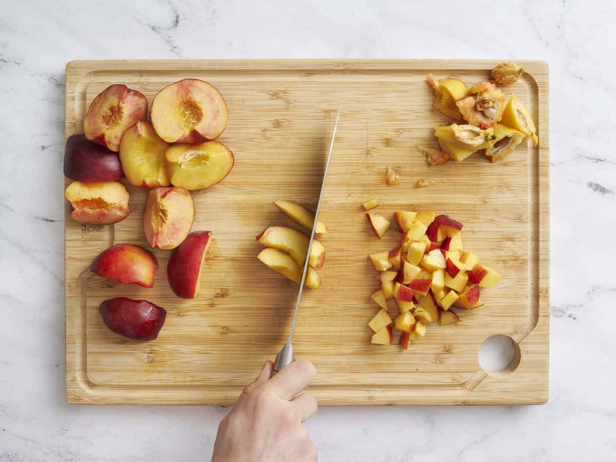 Un couteau en déambuant les pêches fraîches sur une planche à découper en bois.