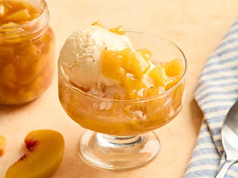 Vanilla ice cream and peach sauce in a glass bowl.