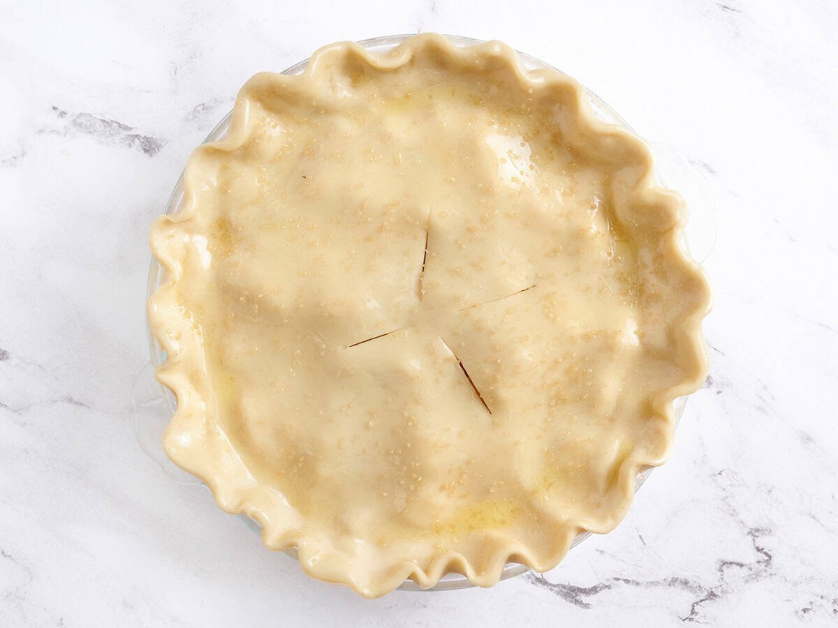 Une tarte aux pêches non cuite dans un plat à tarte.