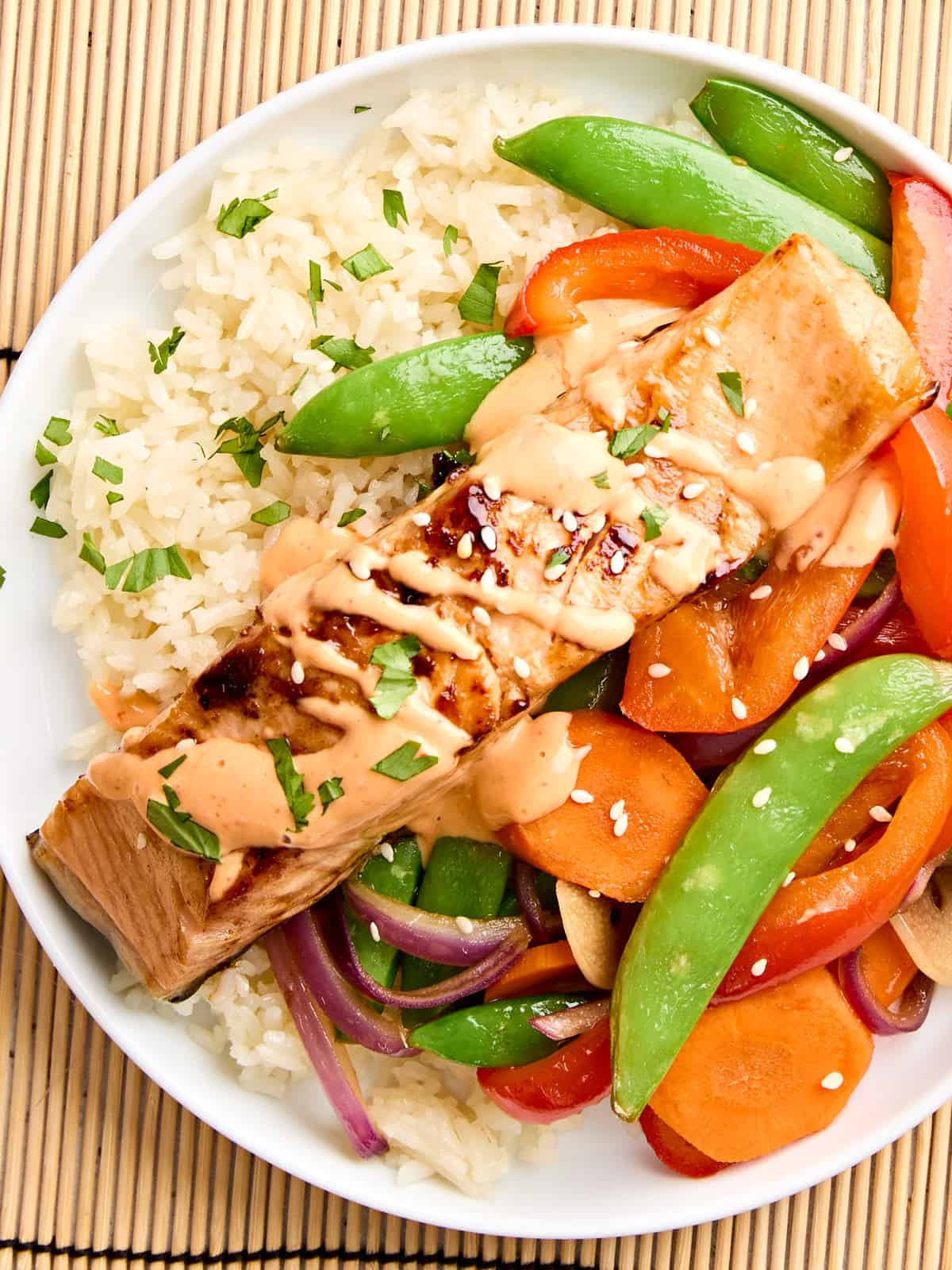 Vue aérienne du saumon teriyaki et de la mayonnaise Sriracha dans une assiette avec des légumes sautés et du riz.