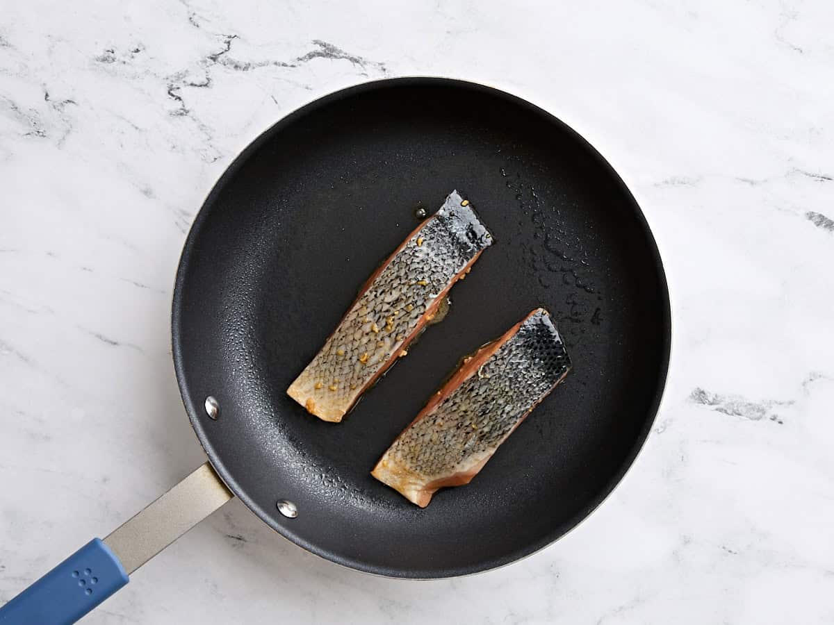 Filets de saumon teriyaki cuisinant dans une poêle.