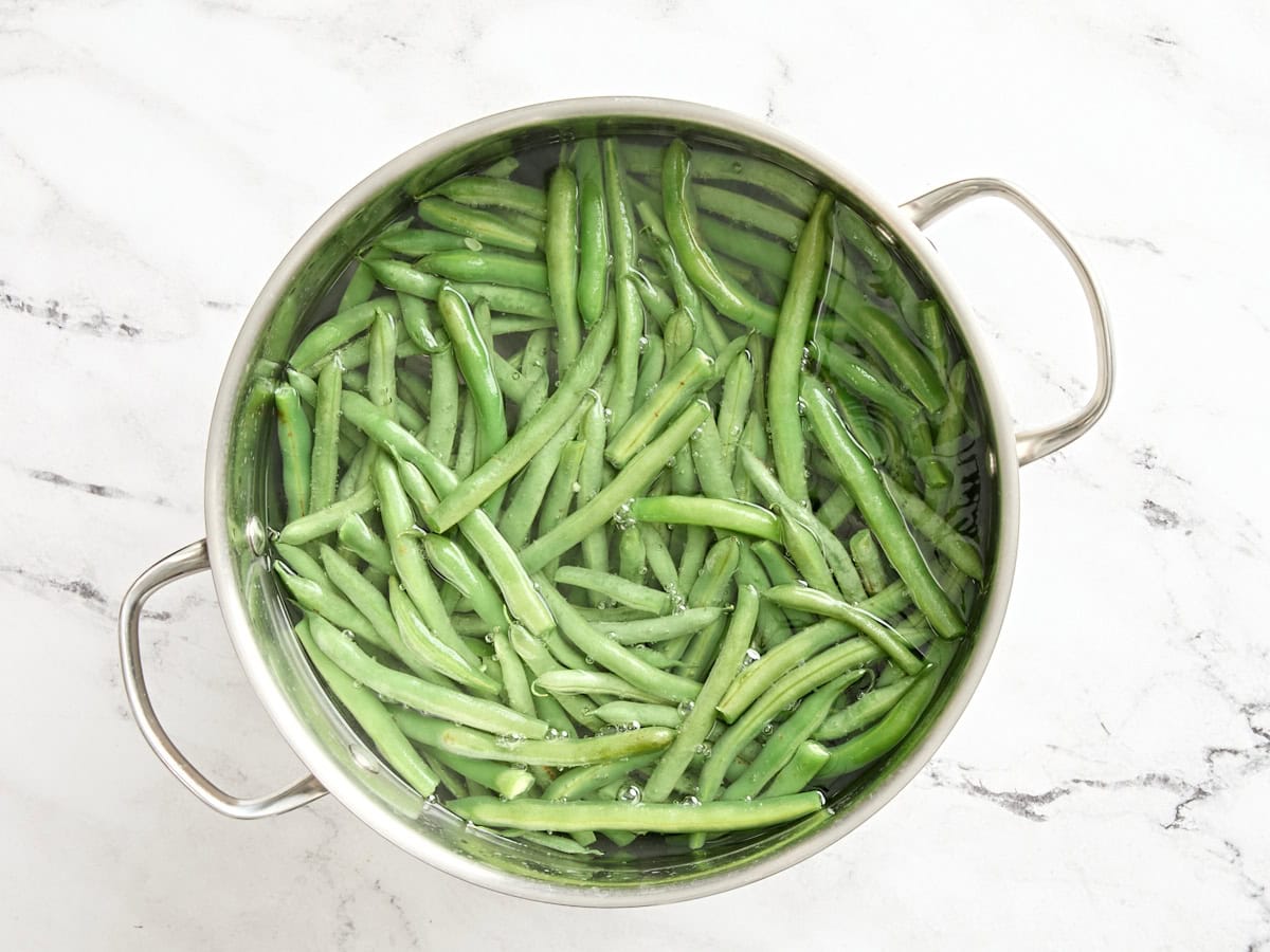 Les haricots verts frais blanchissent dans l'eau chaude.