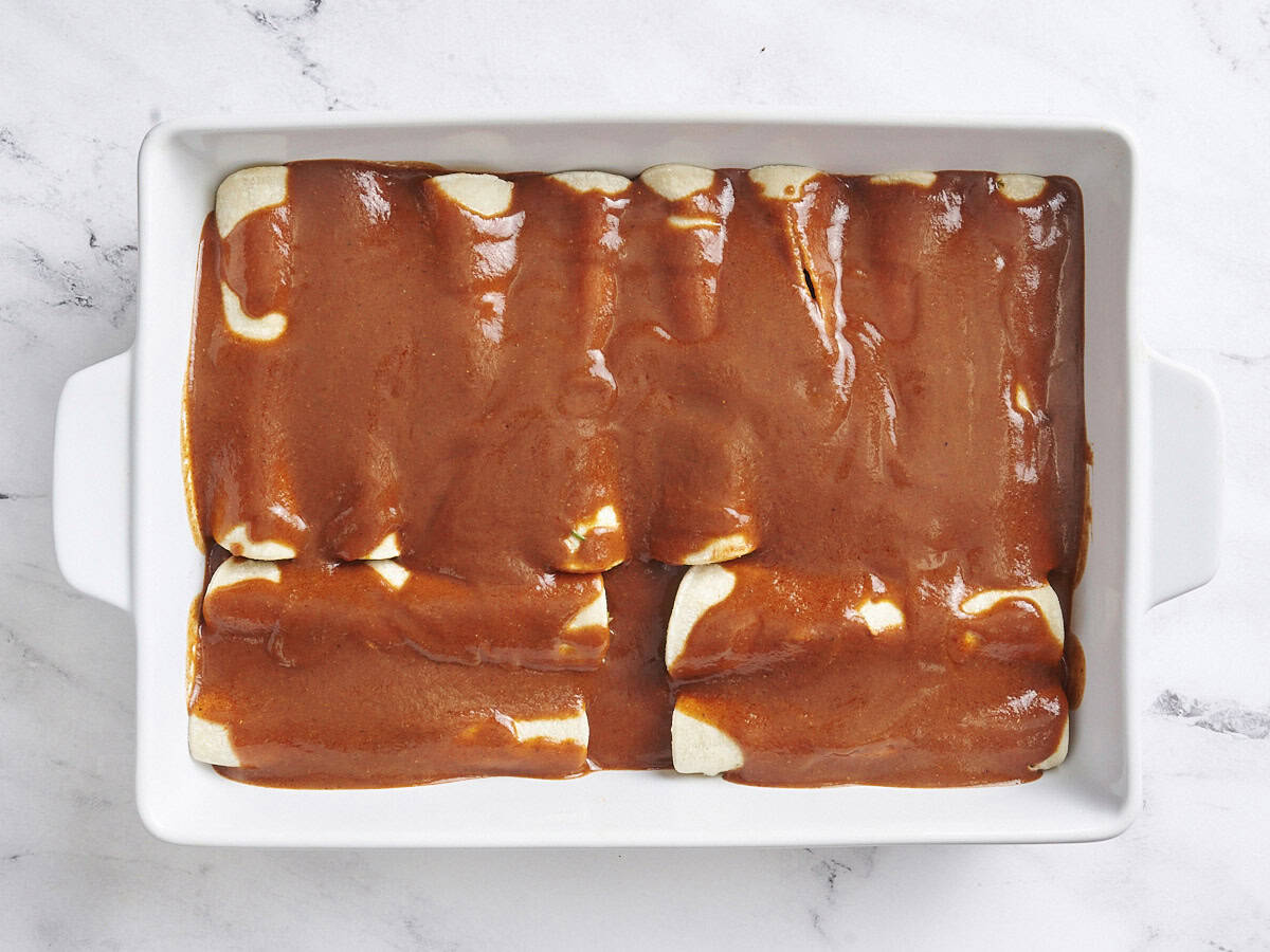 Enchiladas de boeuf dans un plat de cuisson garni de sauce enchilada.