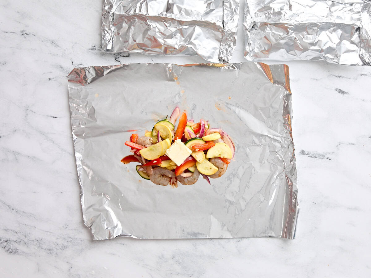 Mélange de crevettes et de légumes sur un carré de papier d'aluminium.