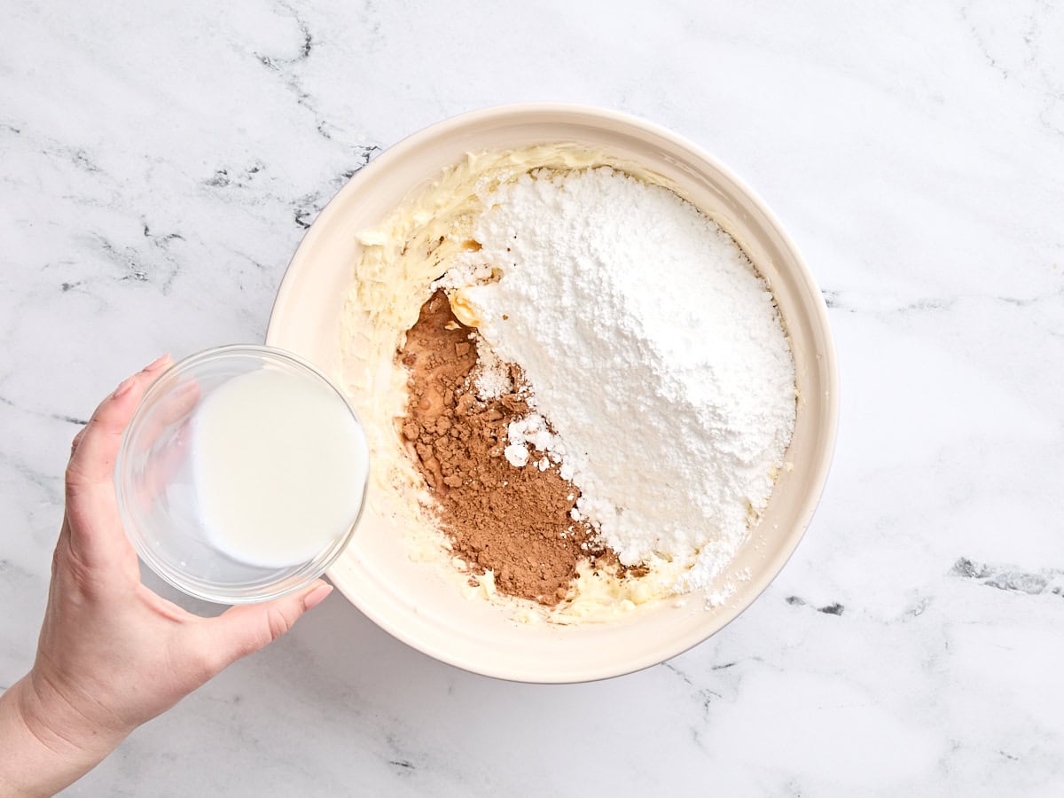 Le lait est ajouté à un bol de poudre de cacao et de sucre en poudre.