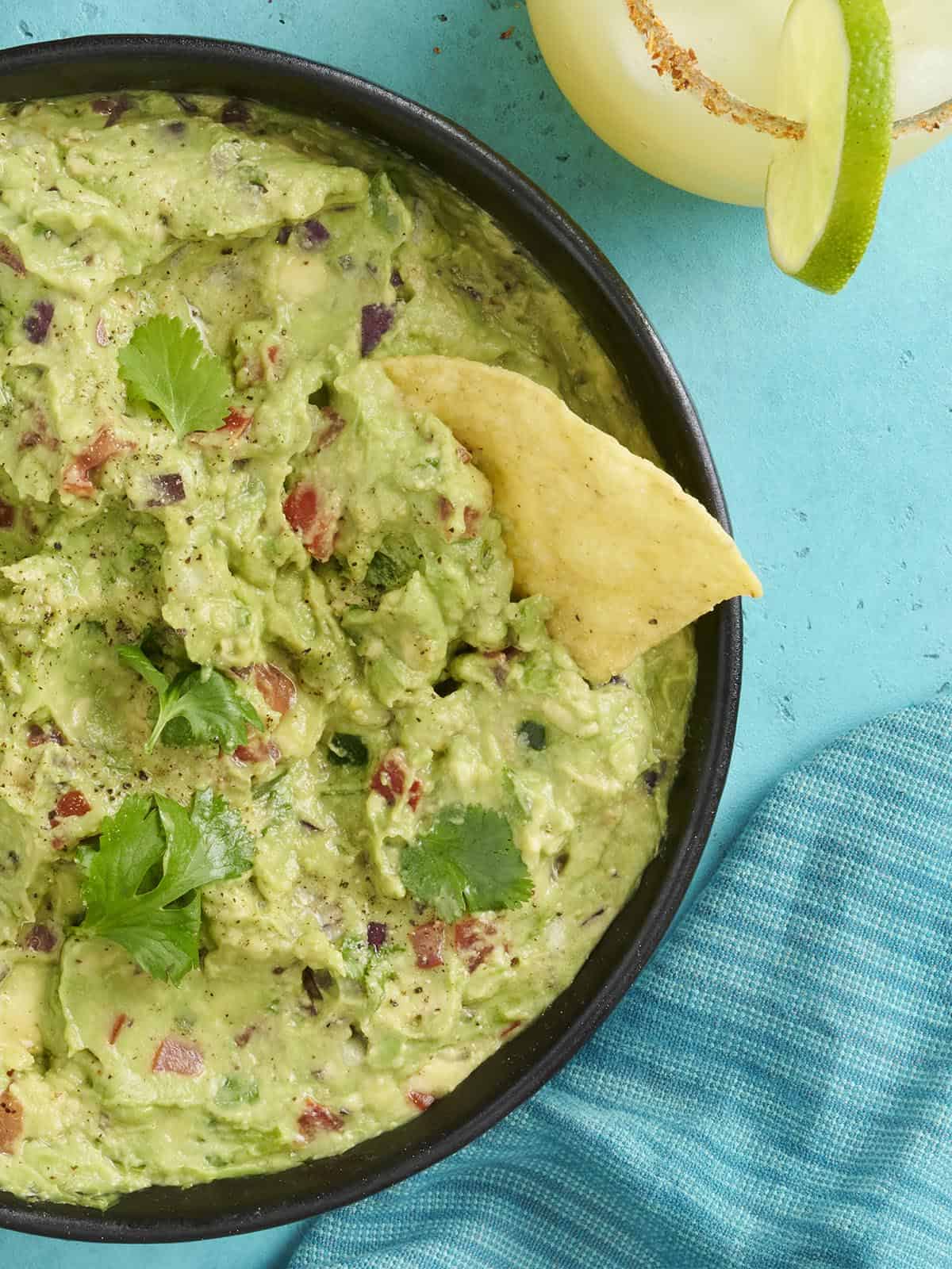 Vue de près au-dessus d'un bol de guacamole avec une puce trempée dedans.