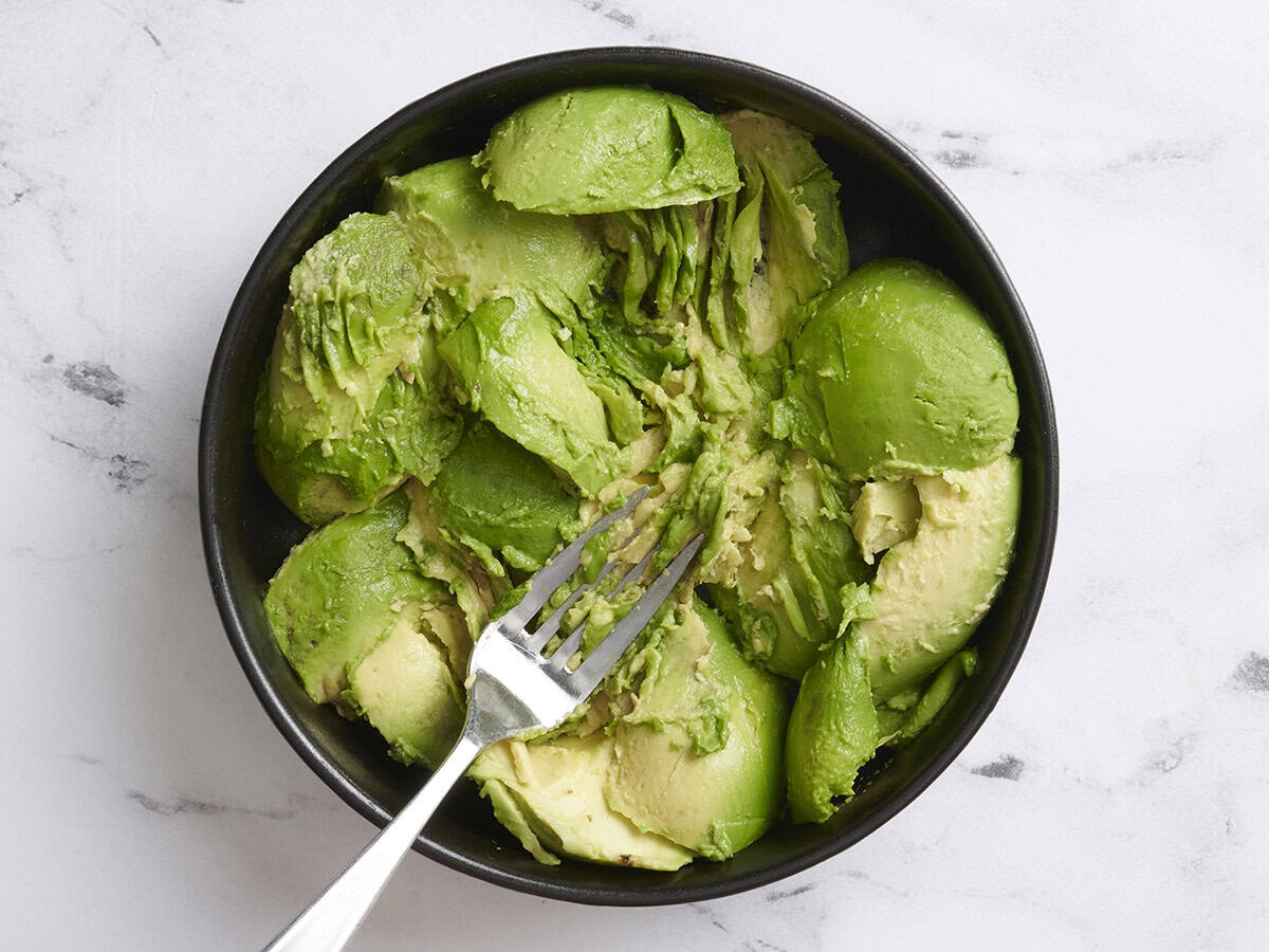 Une fourchette d'écrase d'avocat se divise dans un bol.