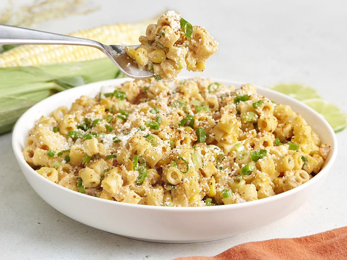 Vue latérale de la salade de pâtes de maïs de rue dans un bol avec une fourchette en prenant.