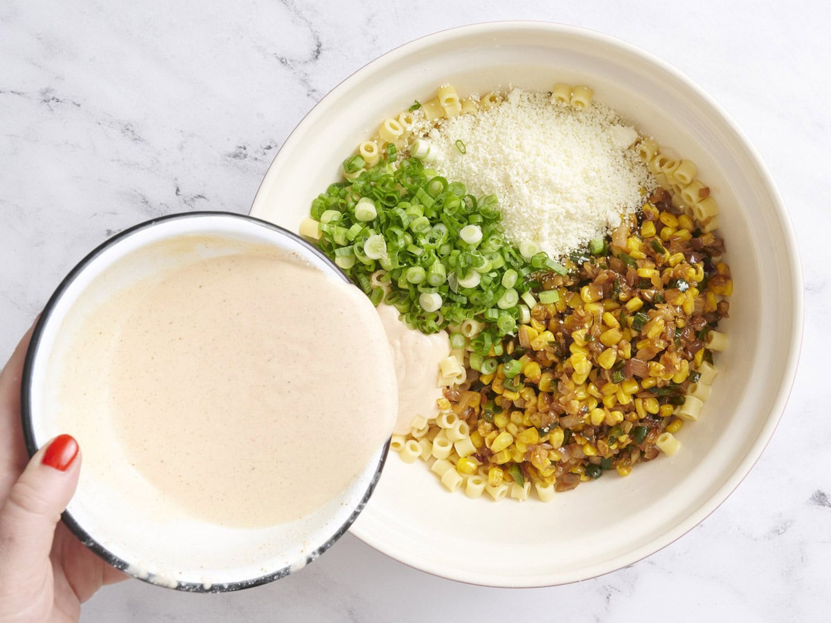 Pâtes cuites, mélange de maïs et de légumes, oignons verts, fresques Queso et vinaigrette dans un bol.