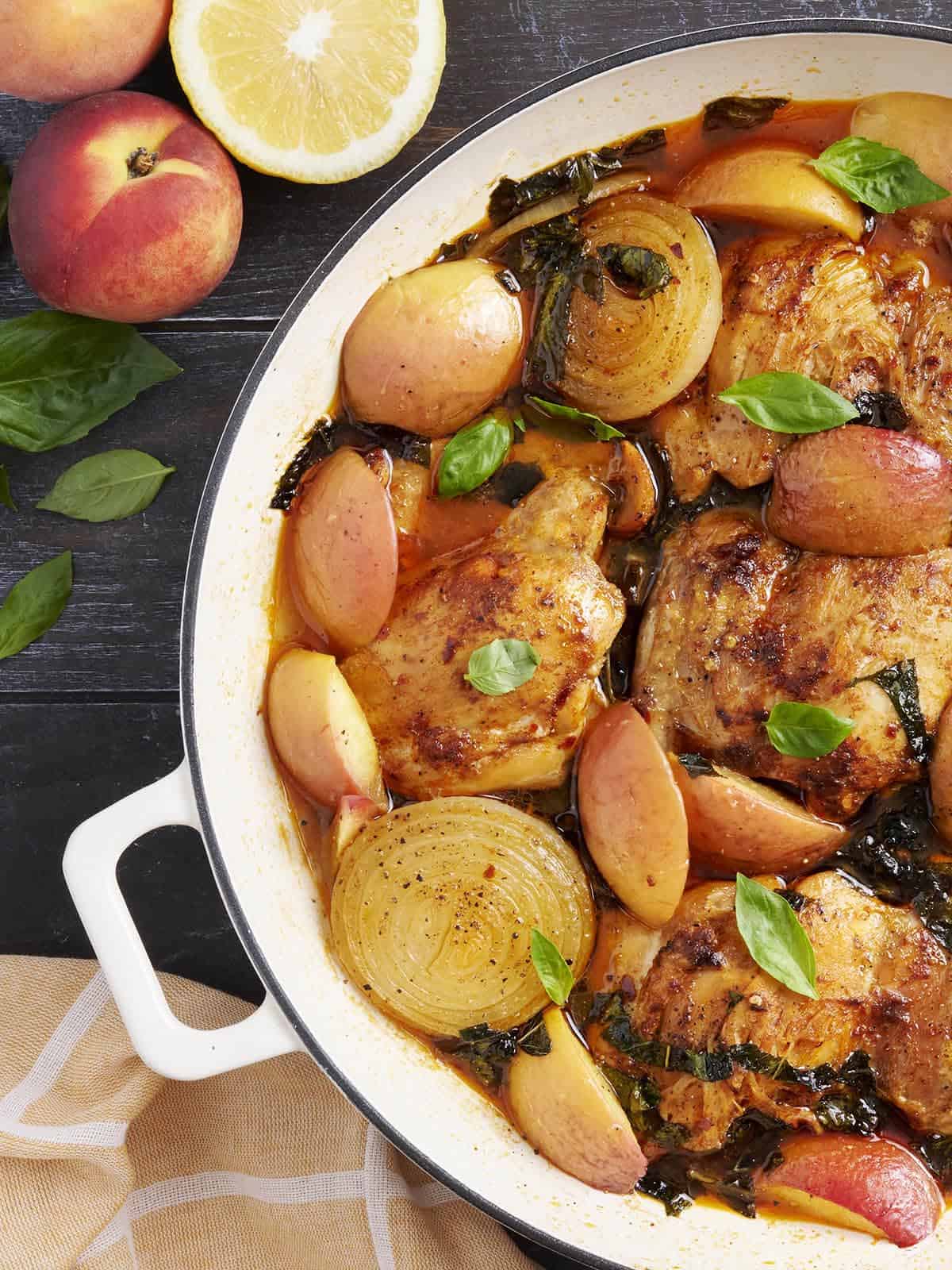 Au-dessus de gros plan du poulet braisé et des pêches dans une poêle.