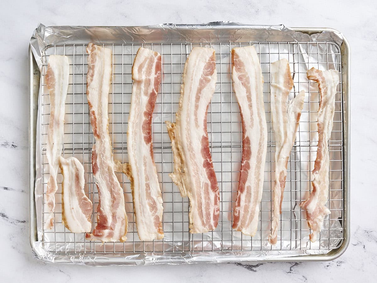 Tranches de bacon cru sur une plaque à pâtisserie.