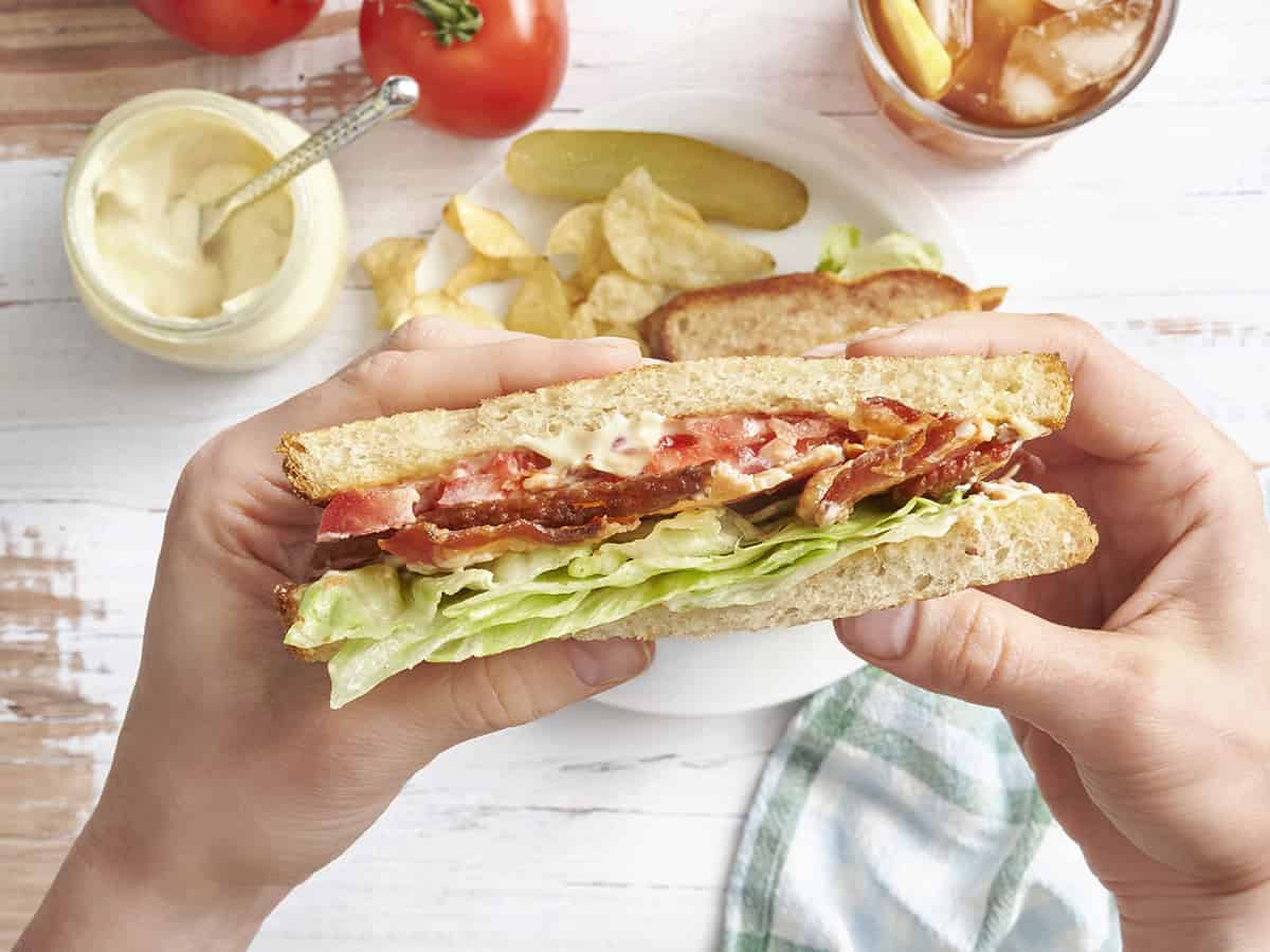 Vue aérienne des mains tenant un sandwich BLT.
