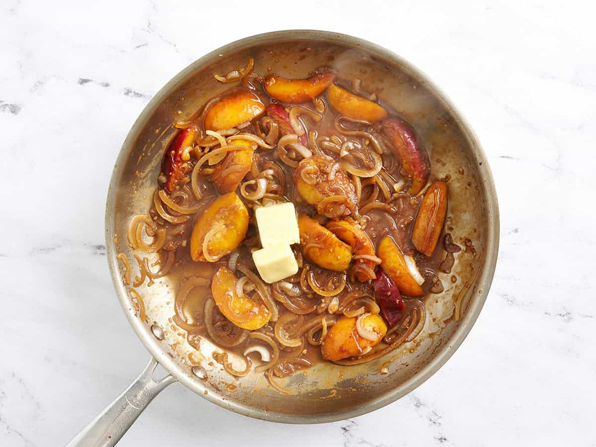 Le beurre ajouté à une sauce pêche et oignon dans une poêle.