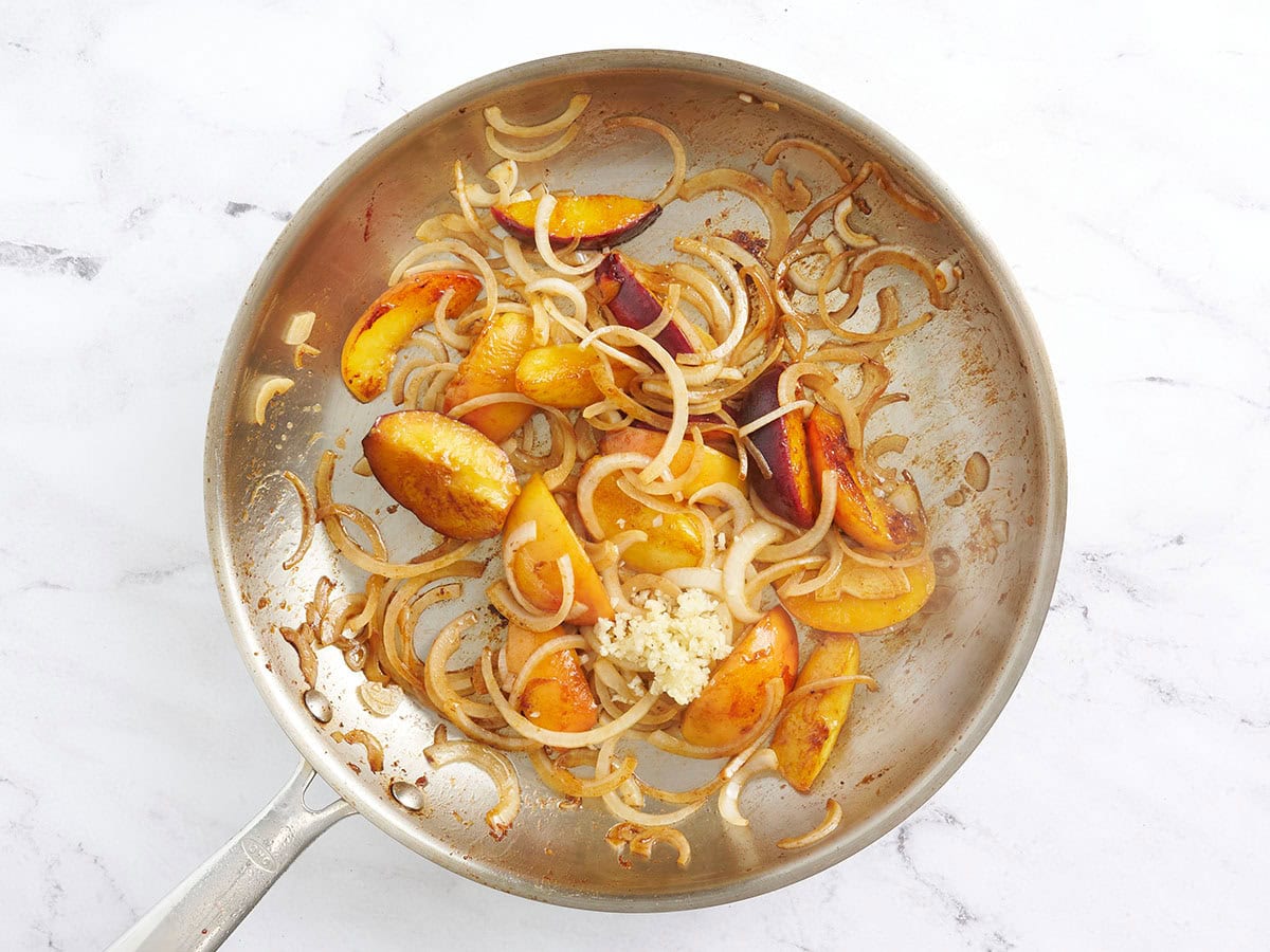 Stices de pêche et oignons sautés dans une poêle avec de l'ail haché.