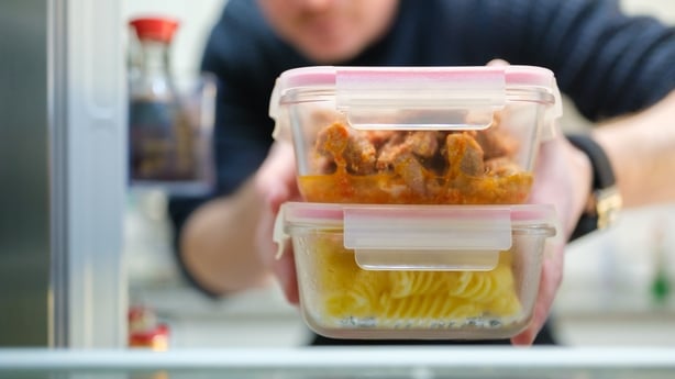 Homme prenant des pâtes cuites et des restes de poulet du réfrigérateur