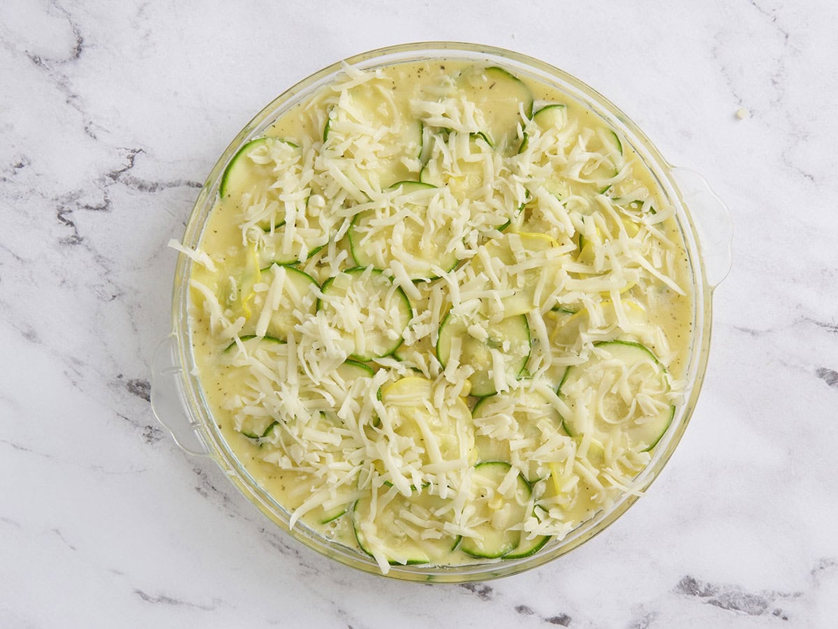 Les ingrédients pour la courgette et la tarte au maïs dans une poêle garnie de fromage râpé.