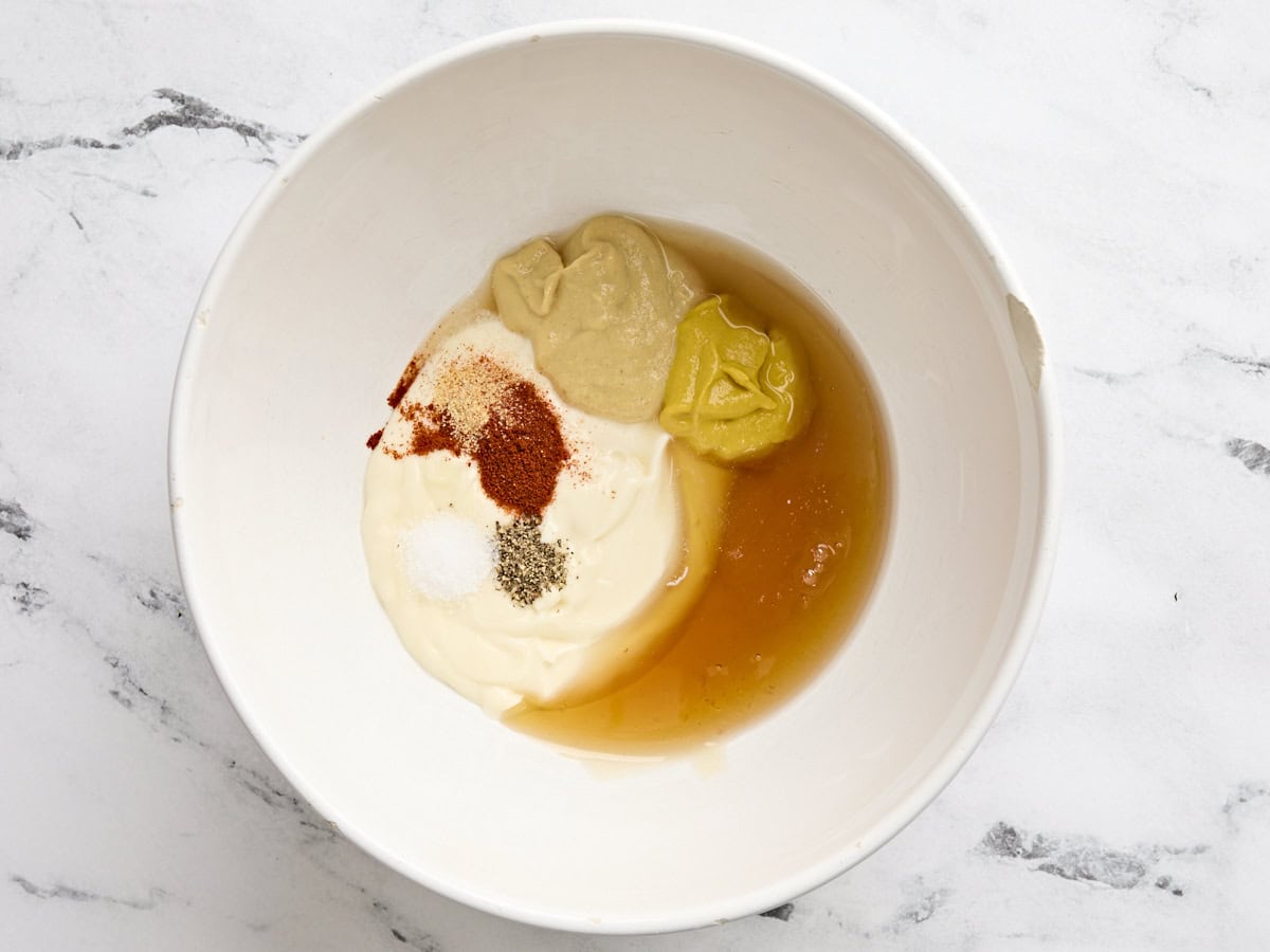 Mayo, moutarde, miel, vinaigre de cidre de pomme et assaisonnements dans un bol.