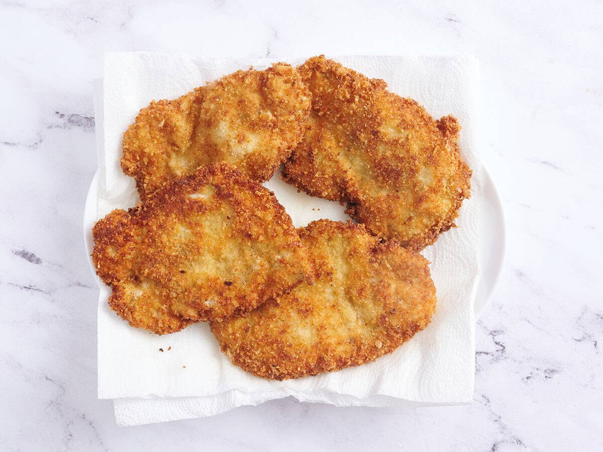 Quatre schnitzels de poulet reposant sur des serviettes en papier.