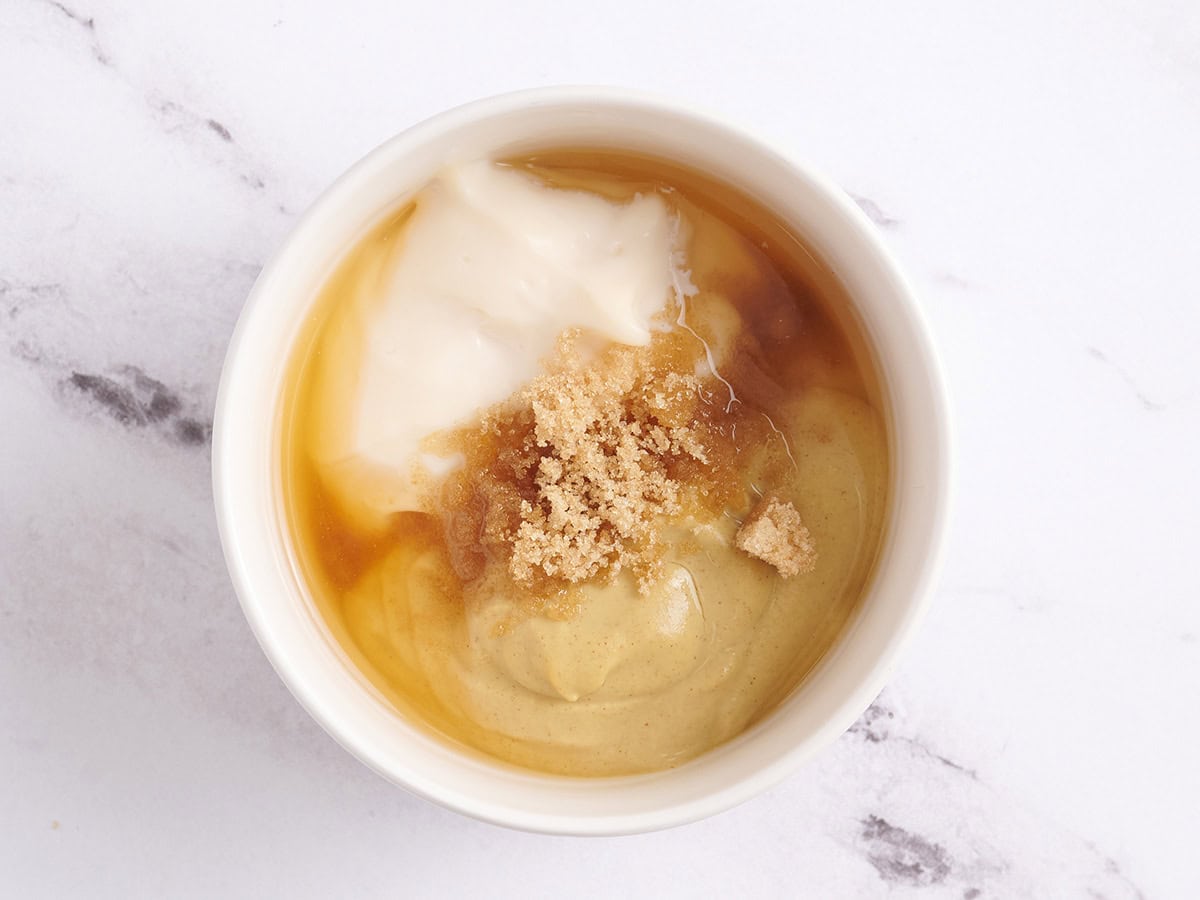 Sucre brun, mayonnaise, moutarde et vinaigre de cidre de pomme dans un bol pour faire de la sauce à la moutarde.