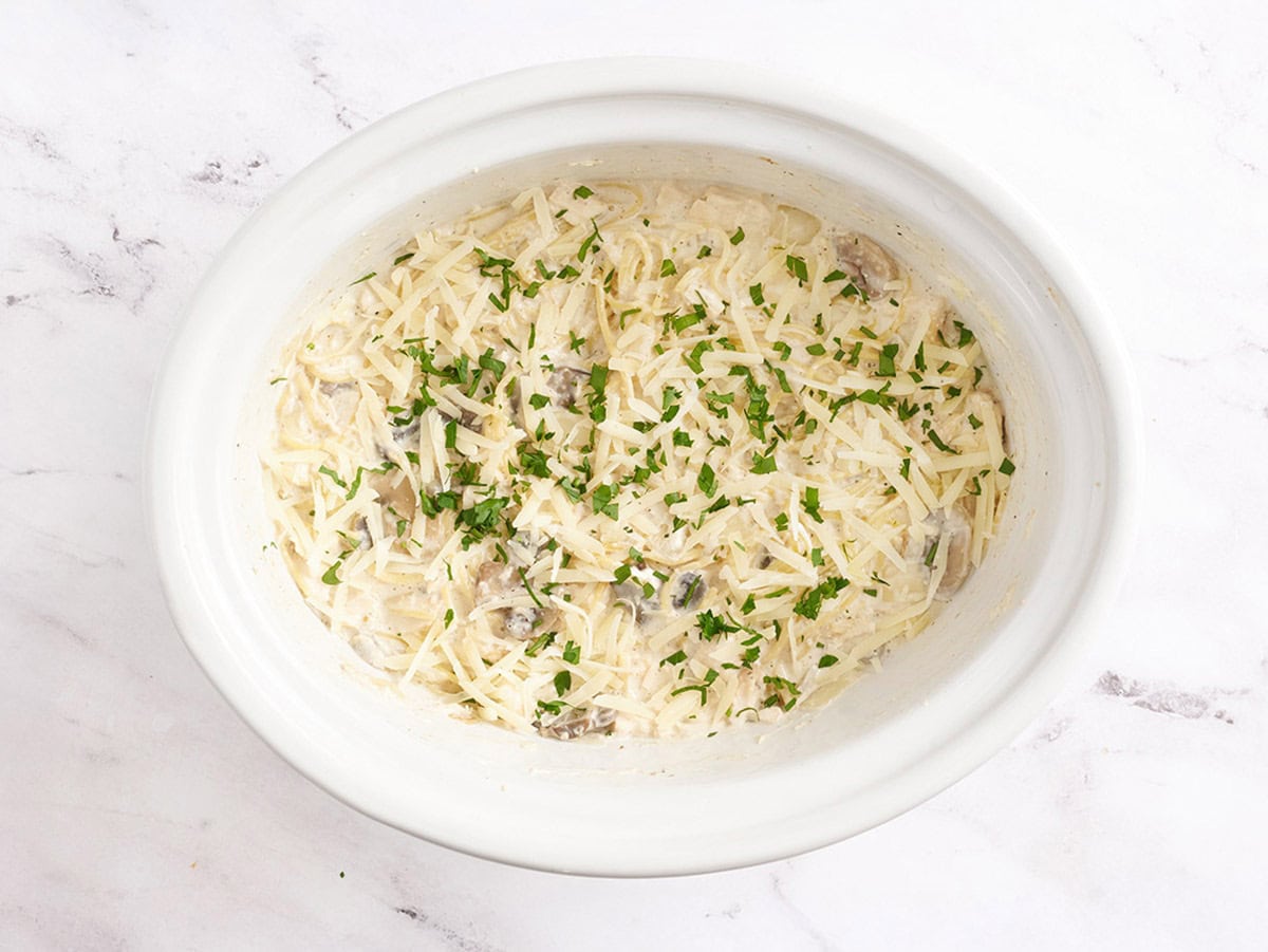 Recette de tétrazzini au poulet à la mijoteuse dans une mijoteuse, garnie de parmesan et de persil frais.