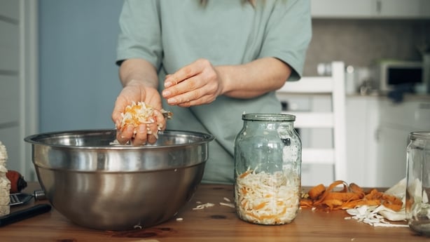 La femme prépare le chou blanc mariné, transfère le chou d'un bol en métal dans un bocal. Produit fermenté