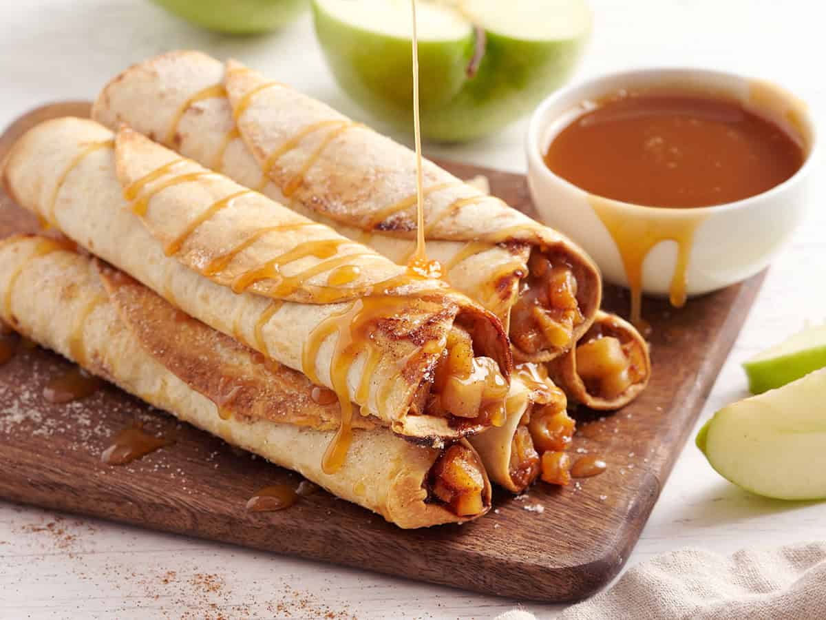 Une pile de flautas aux pommes maison arrosées de sauce au caramel.