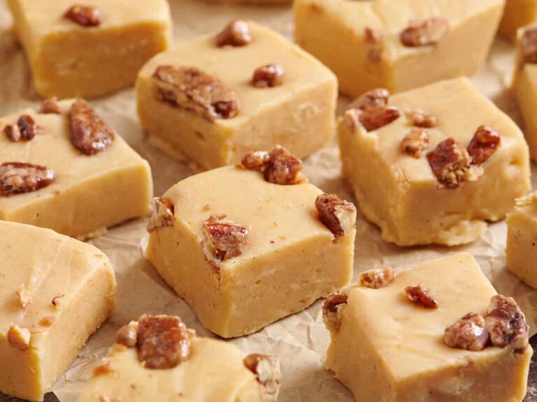 Close up side view of homemade pumpkin spice fudge on parchment paper.