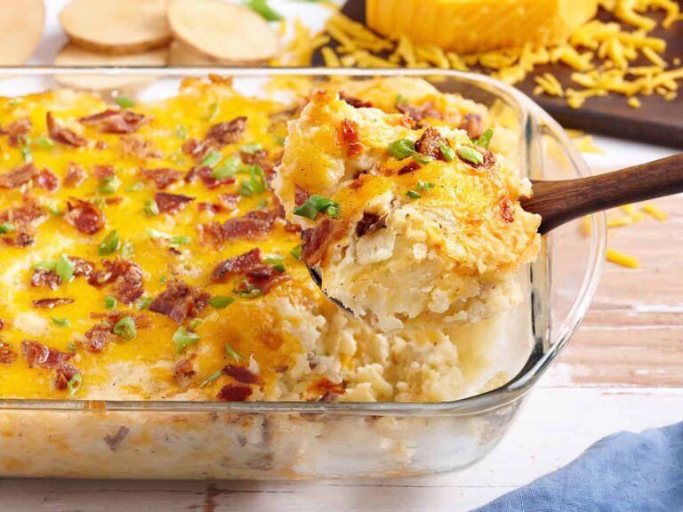 Side view of a twice baked potato casserole with a spoon taking some out the dish.