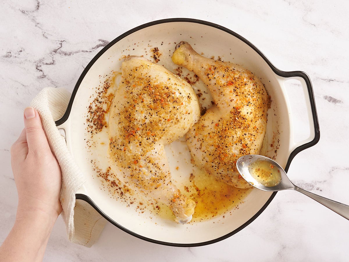 Une cuillère en arrosant les cuisses de poulet après une heure de cuisson.