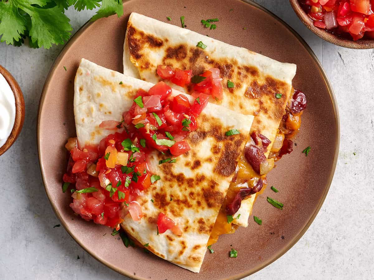 Vue aérienne de deux quesadillas aux haricots rouges sur une assiette avec salsa.