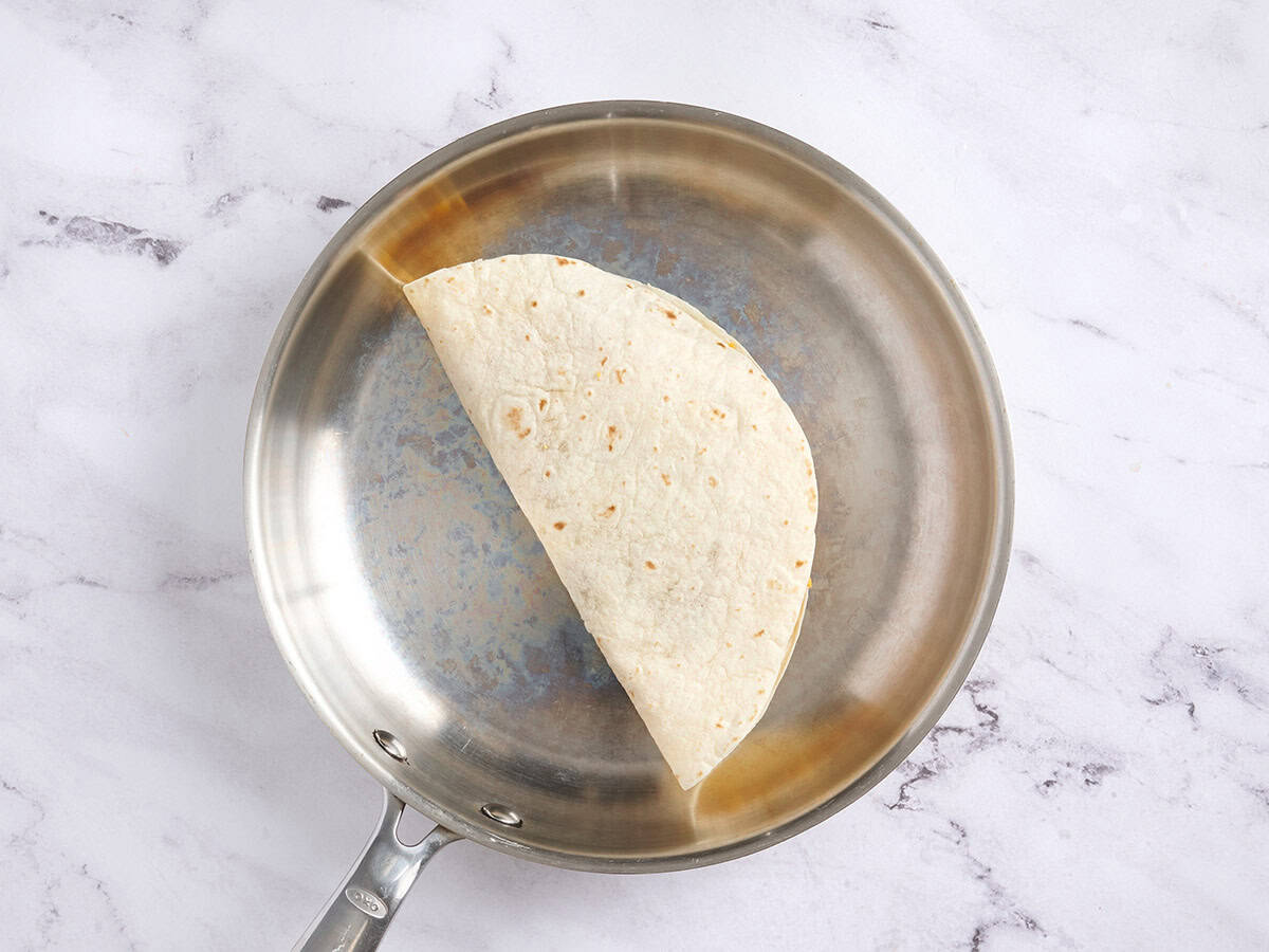 Une tortilla pliée cuisant dans une poêle.