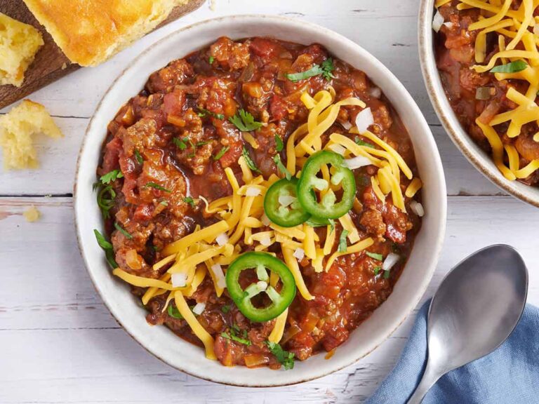 Overhead view of a bowl of Texas chili topped with shredded cheese and jalapeno slices.