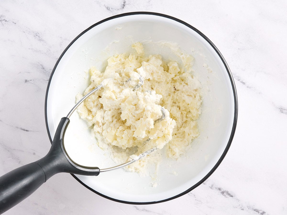 Peau de pomme de terre remplissant un bol avec un presse-purée.