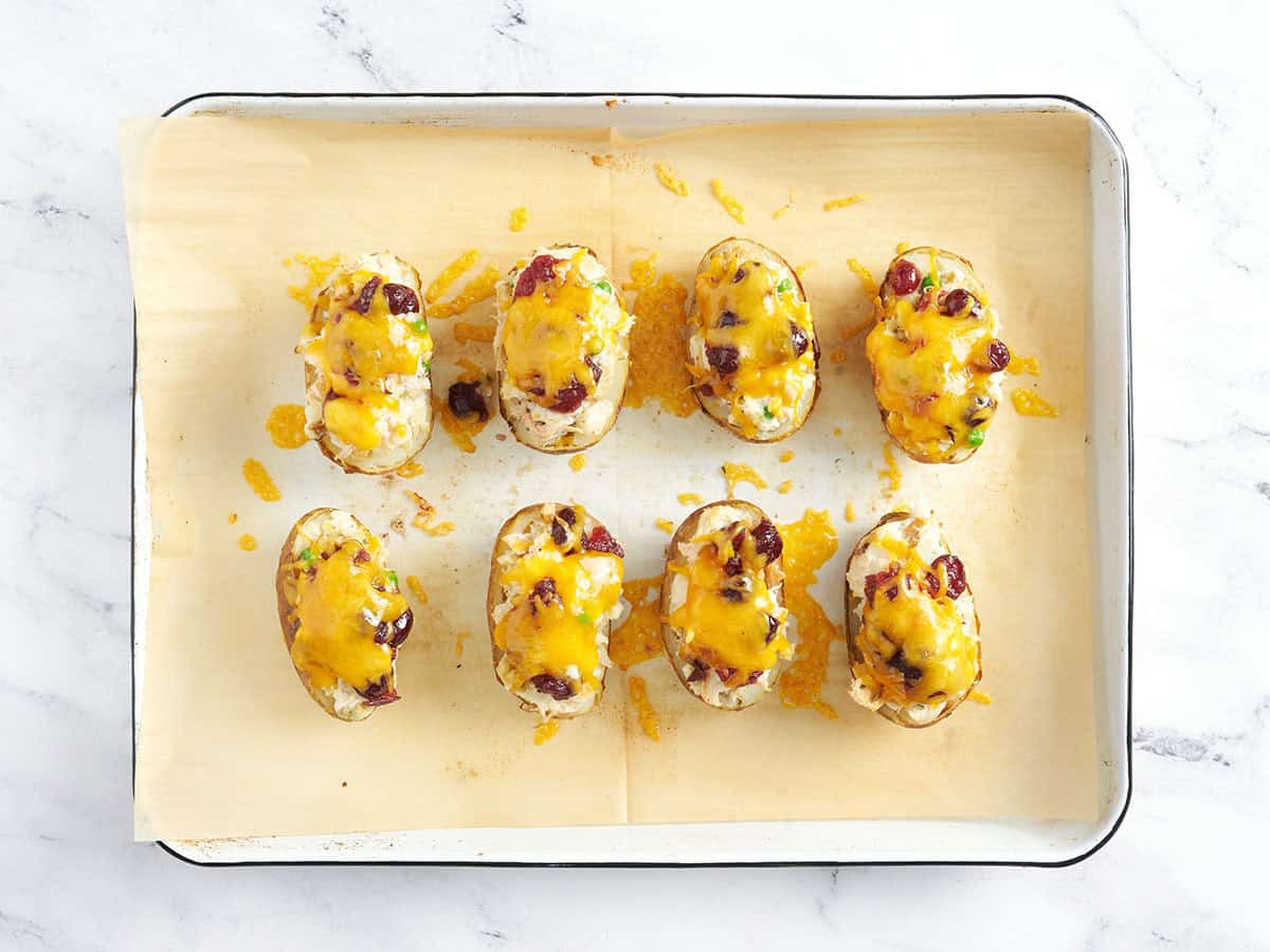 Quatre pommes de terre sur une plaque à pâtisserie avec de l'huile et des assaisonnements