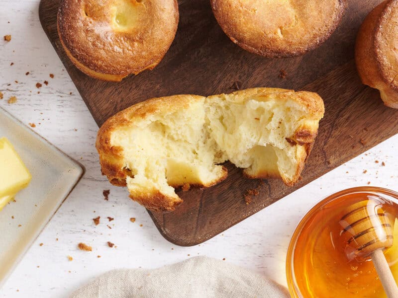 Popover déchiré sur une planche à découper avec un bol de miel