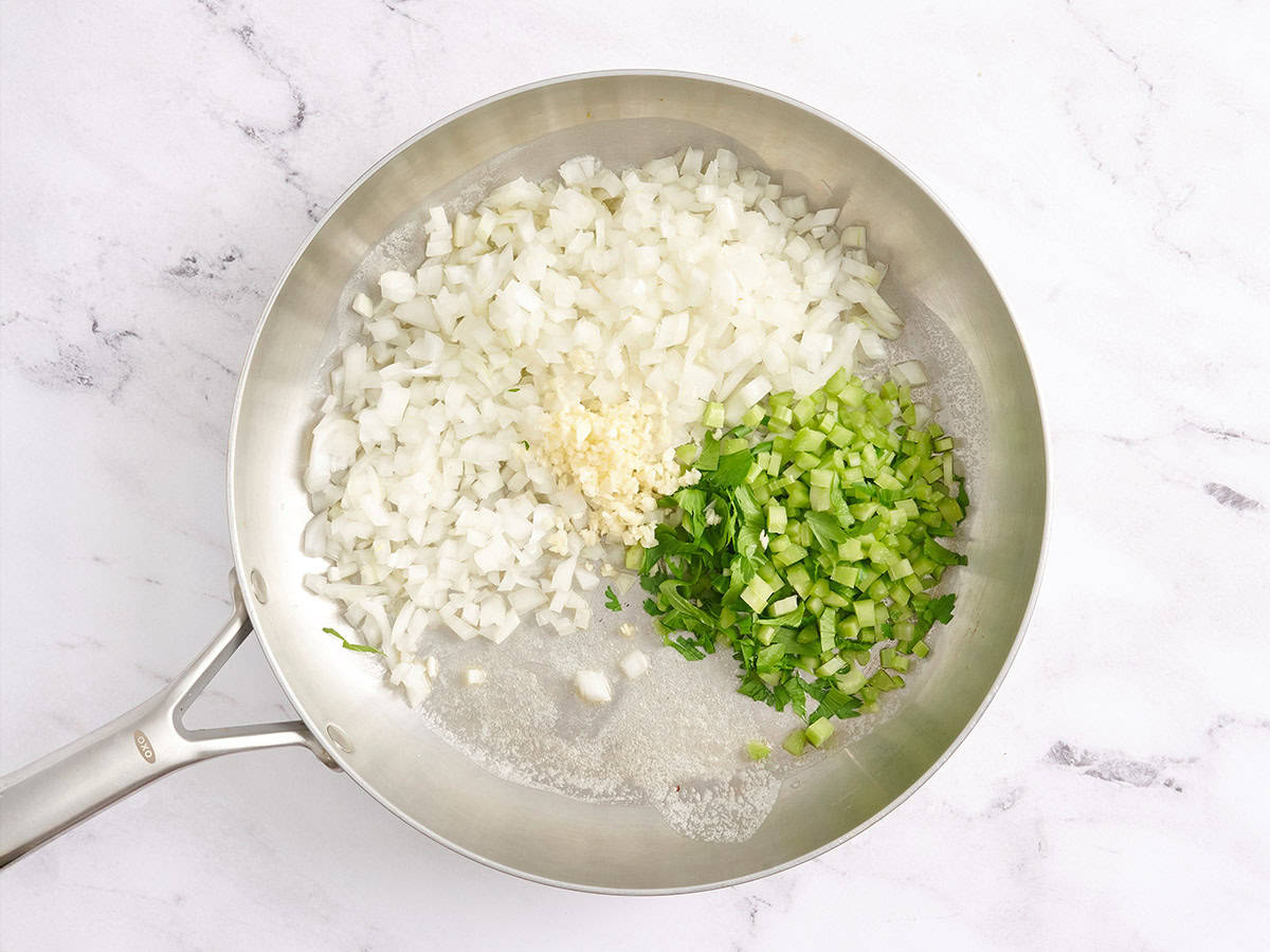 Oignons, céleri, ail et beurre dans une poêle.