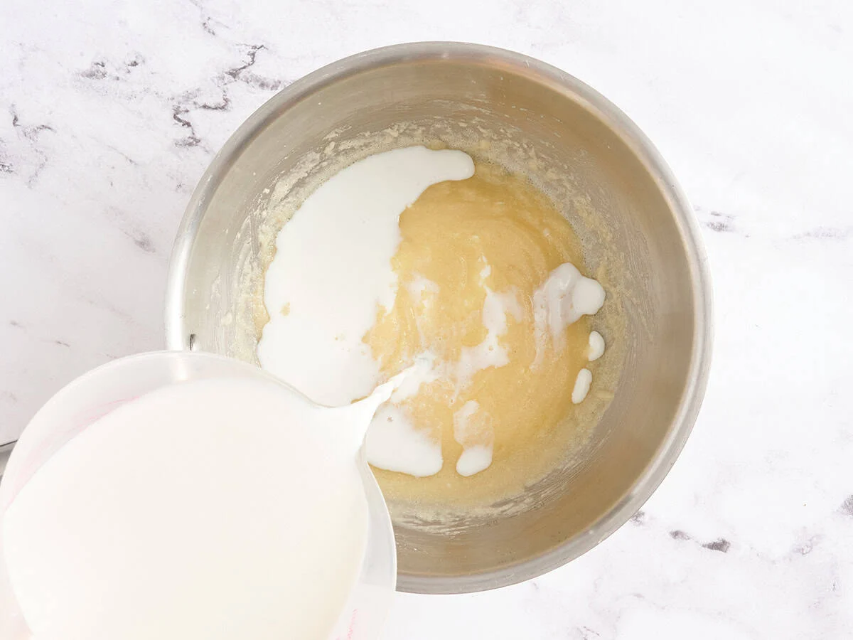 Le lait est versé lentement dans un roux.