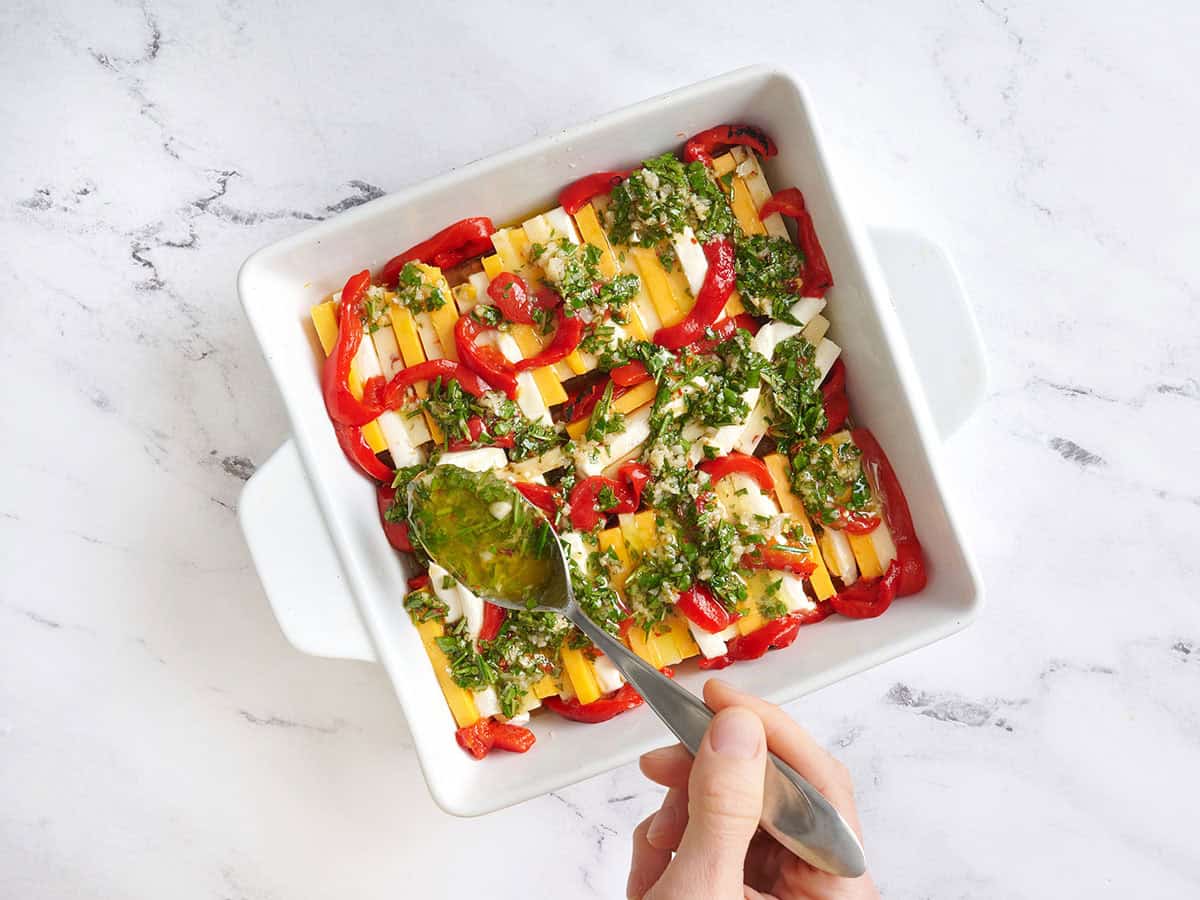 Fromage en tranches disposé dans un plat allant au four et garni d'une marinade.