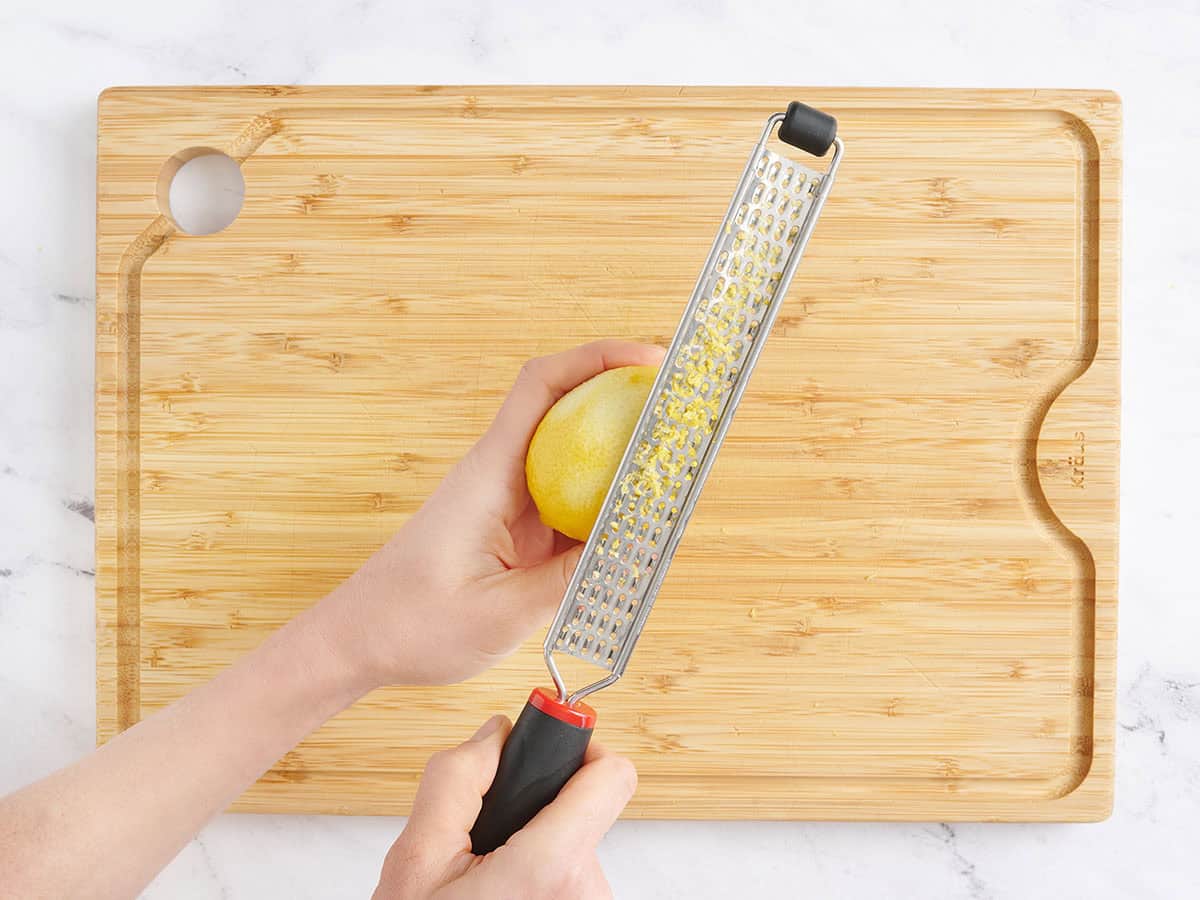 Une main utilisant un zesteur pour zester un citron.