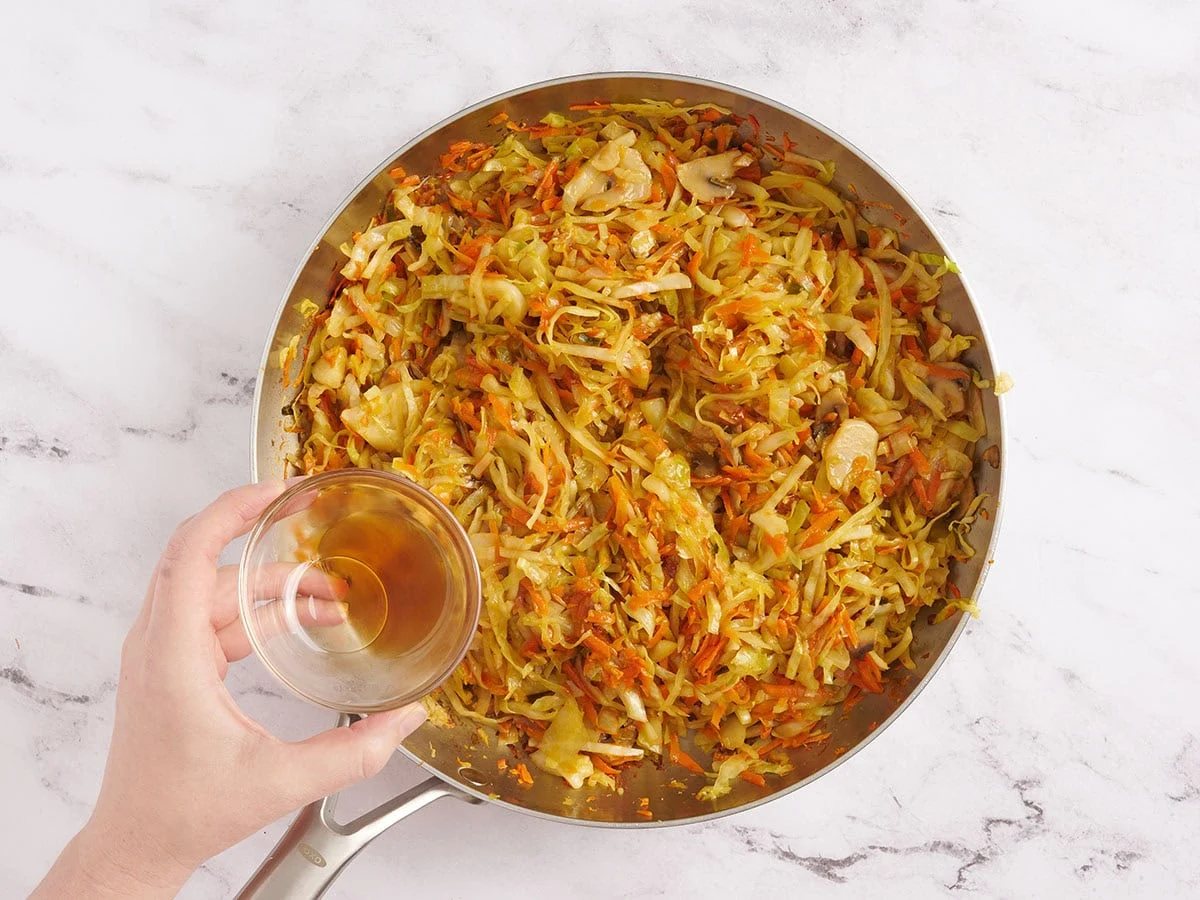 L'huile de sésame est versée dans une poêle de légumes sautés.