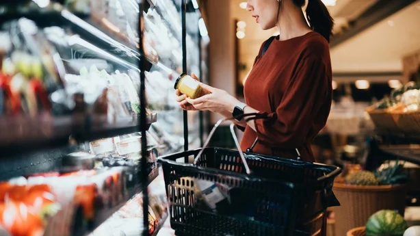   femme dans un magasin lisant une étiquette alimentaire