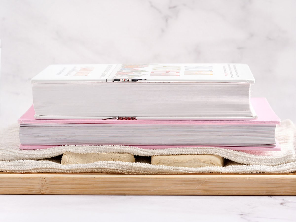 Tofu pressé avec des livres de cuisine.