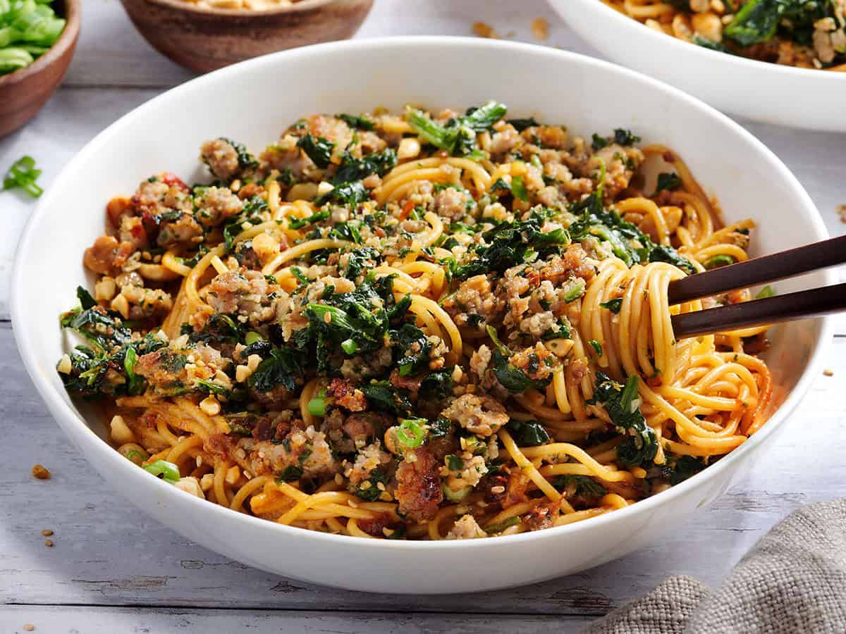 Vue latérale d'un bol de nouilles dan dan avec des baguettes.Vue aérienne d'un bol de nouilles dan dan avec des baguettes.