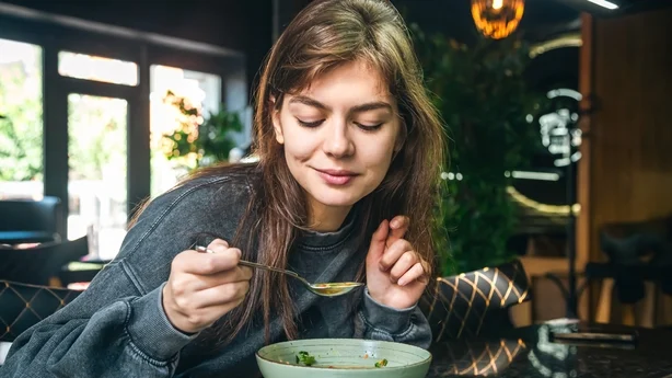 femme mangeant de la soupe aux légumes dans un café